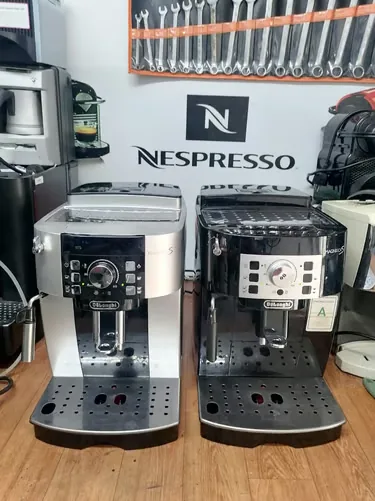 Deux machines De’Longhi réparées devant le mur d’outils de l’atelier